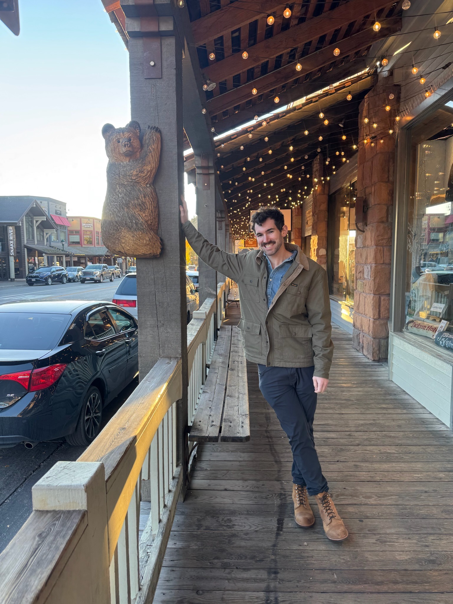 Aaron downtown leaning against a pole with a bear